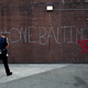 A police officer walks by a tagging reading “One Baltimore” on the corner of North and Pennsylvania Avenues in Baltimore on May 2, 2015, a day after authorities released a report on the death of Freddie Gray. (Patrick Smith/Getty Images)